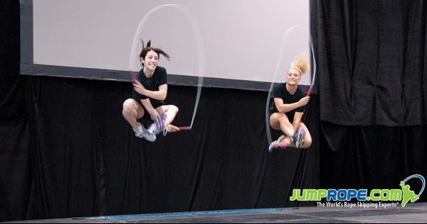 Two people jump roping on a stage with a banner for the GPC Canada Super Show in the background.